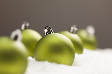 Image showing Green Christmas Ornaments on Snow Over a Grey Background