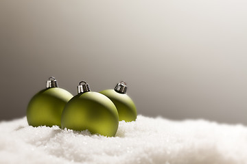 Image showing Green Christmas Ornaments on Snow Over a Grey Background