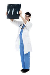 Image showing Nurse holding x-ray sheet against light to examine