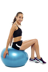 Image showing Pretty woman relaxing on big blue exercise ball