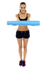 Image showing Woman holding a blue mat in her outstretched arms