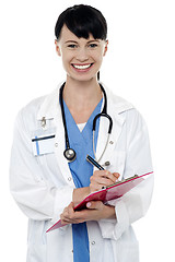 Image showing Friendly doctor updating medical record of a patient