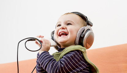 Image showing young child on couch with headphone