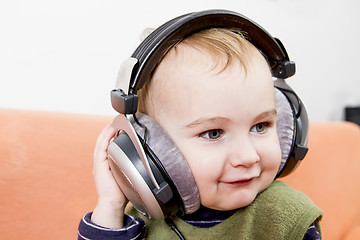 Image showing young child on couch with headphone
