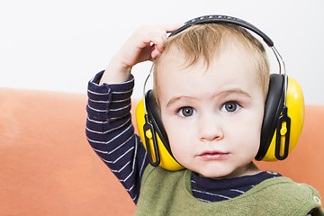 Image showing young child on couch with earmuffs