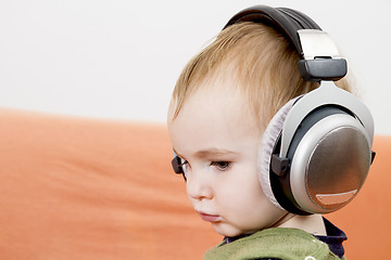 Image showing young child on couch with headphone