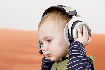 Image showing young child on couch with headphone