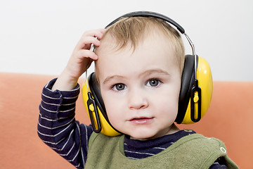 Image showing young child on couch with earmuffs