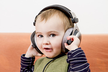 Image showing young child on couch with headphone