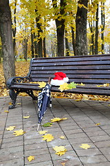 Image showing Santa's cap and an umbrella on a bench. 