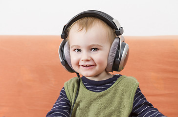 Image showing young child on couch with headphone