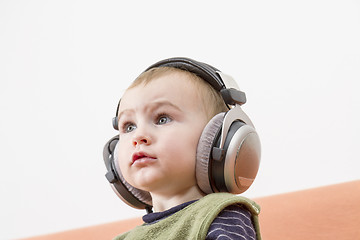 Image showing young child on couch with headphone