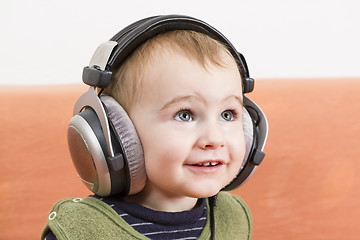 Image showing young child on couch with headphone