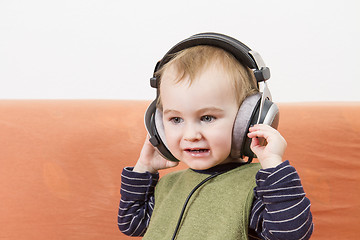 Image showing young child on couch with headphone