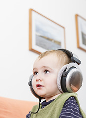 Image showing young child on couch with headphone