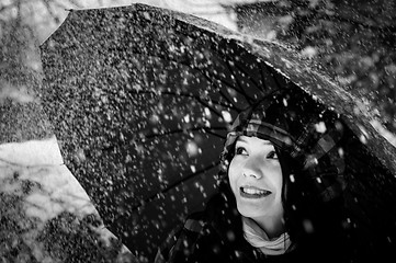 Image showing Young woman with umbrella in a blizzard