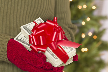 Image showing Woman Wearing Mittens Holding Stacks of Money with Red Ribbon