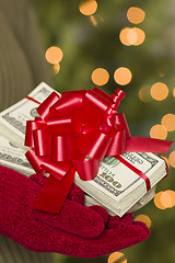 Image showing Woman Wearing Mittens Holding Stacks of Money with Red Ribbon