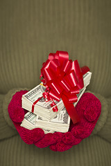 Image showing Woman Wearing Mittens Holding Stacks of Money with Red Ribbon