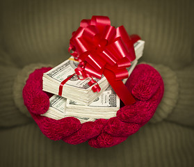 Image showing Woman Wearing Mittens Holding Stacks of Money with Red Ribbon