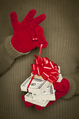 Image showing Woman Wearing Mittens Holding Stacks of Money with Red Ribbon