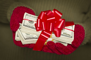 Image showing Woman Wearing Mittens Holding Stacks of Money with Red Ribbon