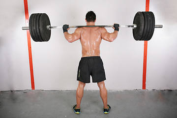 Image showing arms and back of a young muscular man working out with a bar
