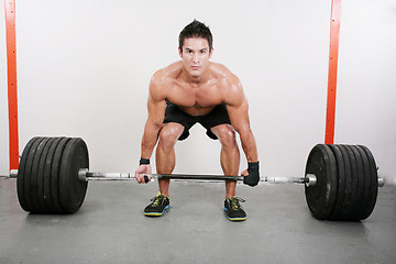 Image showing Young and muscular guy holding a barbell.  Crossfit dead lift ex