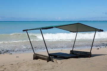 Image showing Table and chairs covered by sand on beach