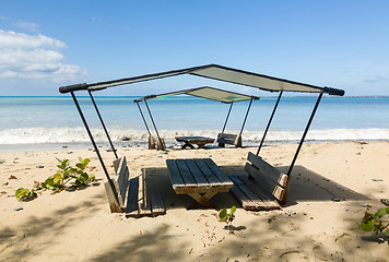 Image showing Table and chairs covered by sand on beach