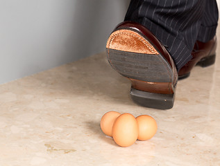 Image showing Man's shoe stamping on three eggs