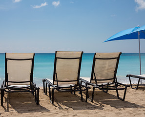 Image showing Three beach loungers and umbrella on sand