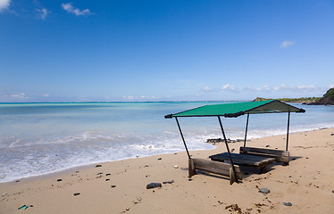 Image showing Table and chairs covered by sand on beach