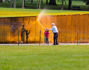 Image showing Man and girl washing wall at Vietnam memorial