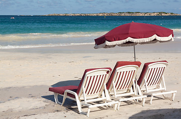 Image showing Three beach loungers and umbrella on sand