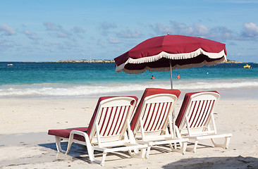 Image showing Three beach loungers and umbrella on sand