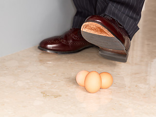 Image showing Man's shoe stamping on three eggs