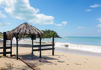 Image showing Table and chairs covered by sand on beach