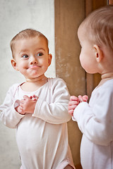 Image showing Baby standing against the mirror