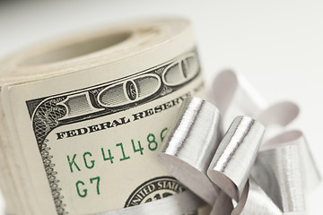 Image showing Roll of One Hundred Dollar Bills Tied Silver Bow on White