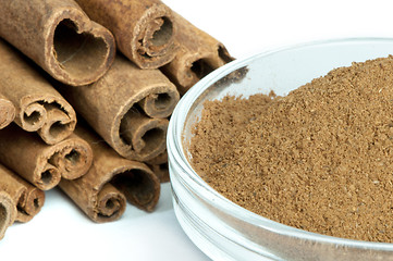 Image showing Powdered cinnamon in bowl and cinnamon sticks