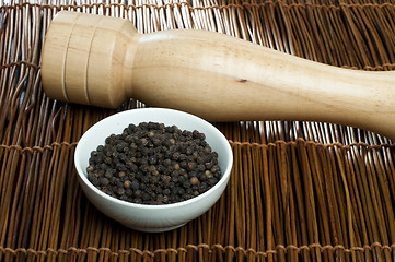 Image showing Bowl with black pepper and wooden pepper mill