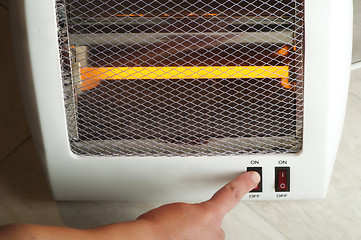 Image showing Electric heater and hand which includes switch