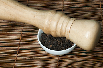 Image showing Bowl with black pepper and wooden pepper mill