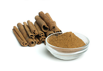 Image showing Powdered cinnamon in bowl and cinnamon sticks