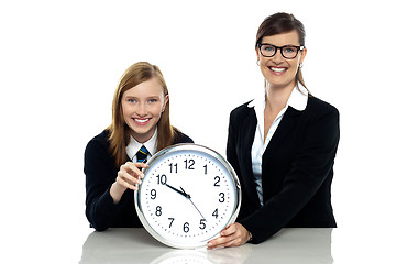 Image showing Pretty student holding clock with her teacher