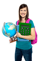 Image showing Smiling female student holding a calculator and globe