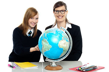 Image showing Teacher and student viewing globe in geography classroom