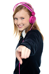 Image showing Pretty musical girl enjoying music and pointing at you