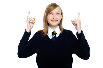 Image showing Amused schoolgirl looking and pointing upwards